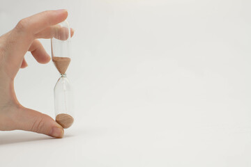 Unrecognizable female hand holding transparent hourglass