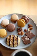 Cup of tea or coffee, cookies, macaroons, chocolate, various nuts and cocoa powder on wooden table. Selective focus.