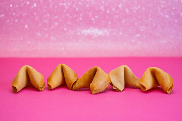 Fototapeta na wymiar Fortune cookies are in a line on a pink and shiny background