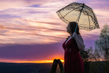 woman with a lace umbrella in the sunset