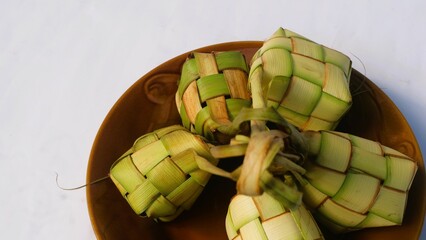 Ketupat (Rice Dumpling) served on plate isolated white. Ketupat is a natural rice casing made from...