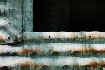 Corroded,. galvanized side of old silo with darkened opening