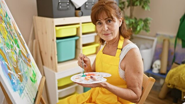 Mature woman painting creatively in art studio, reflecting her artistic passion.