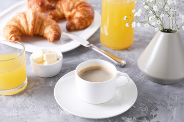 Tasty breakfast. Cup of coffee, butter and fresh croissants on grey table, closeup