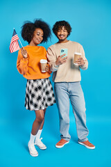 A man and a woman, interracial students, stand beside each other in casual attire against a blue backdrop.