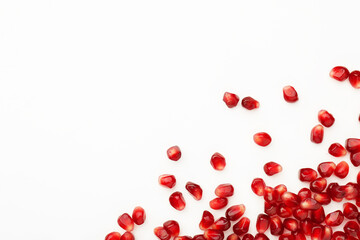 Many ripe juicy pomegranate grains on white background, flat lay. Space for text - obrazy, fototapety, plakaty