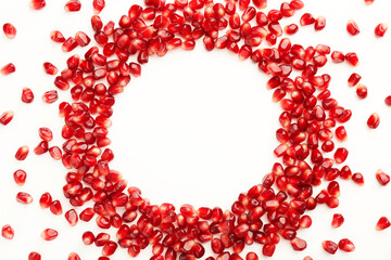 Frame made of ripe juicy pomegranate grains on white background, top view. Space for text