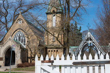 Fototapeta premium white picket fence and Toronto Necropolis located at 200 Winchester Street in Toronto, Canada behind