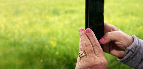 Close up of hands taking pictures outdoor with a smartphone  - obrazy, fototapety, plakaty