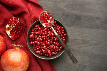 Tasty ripe pomegranates and grains on dark wooden table, flat lay. Space for text