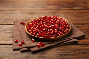 Tasty ripe pomegranate grains on wooden table