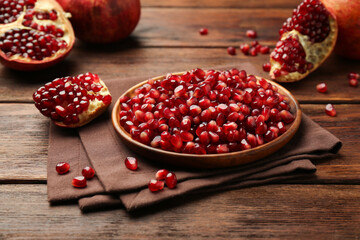 Ripe juicy pomegranates and grains on wooden table
