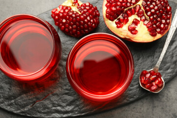 Tasty pomegranate juice in glasses and fresh fruit on grey table, top view