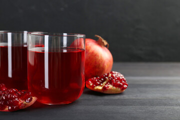 Tasty pomegranate juice in glasses and fresh fruits on black wooden table, closeup. Space for text