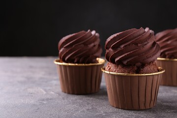 Delicious chocolate cupcakes on grey textured table, closeup. Space for text
