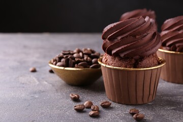 Delicious chocolate cupcakes and coffee beans on grey textured table, closeup. Space for text