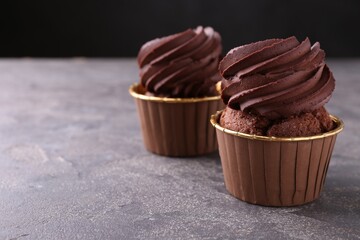 Delicious chocolate cupcakes on grey textured table, closeup. Space for text