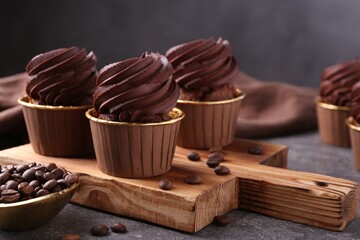 Delicious chocolate cupcakes and coffee beans on grey textured table, closeup