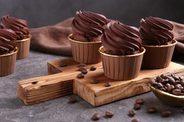Delicious chocolate cupcakes and coffee beans on grey textured table, closeup