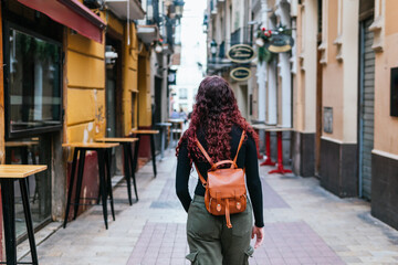 A female traveler with a backpack walks through the streets of the center of a Spanish city, there...