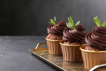 Delicious chocolate cupcakes with mint on black textured table. Space for text