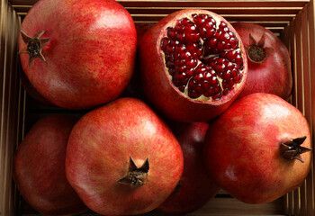 Ripe pomegranates in wooden crate, top view