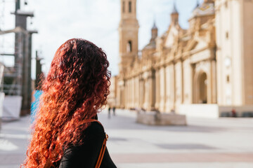 Unrecognizable woman from behind observing the Basilica del Pilar on her visit through the streets...