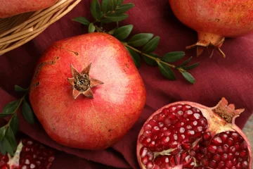 Fotobehang Fresh pomegranates and green leaves on table, top view © New Africa