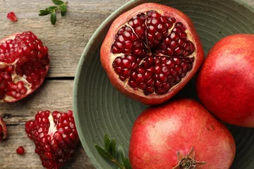 Fotobehang Fresh pomegranates and green leaves on wooden table, flat lay © New Africa