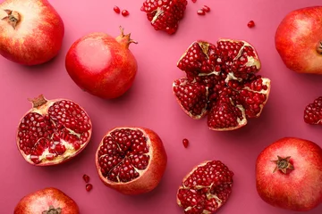 Fotobehang Whole and cut fresh pomegranates on pink background, flat lay © New Africa