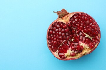 Cut fresh pomegranate on light blue background, top view. Space for text