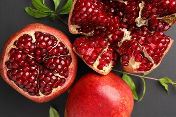 Fresh ripe pomegranates and leaves on grey background, top view