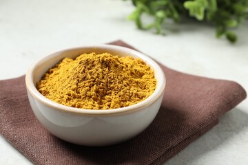 Curry powder in bowl on white table, closeup