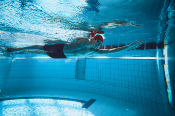 Champion. Young man, swimmer in motion in poo reaching the edge, training swimming techniques and speed. Concept of professional sport, health, endurance, strength, active lifestyle - obrazy, fototapety, plakaty