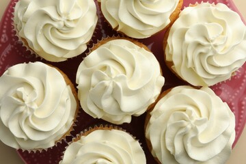 Tasty vanilla cupcakes with cream on beige background, flat lay