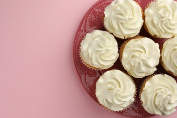 Tasty vanilla cupcakes with cream on pink background, top view. Space for text