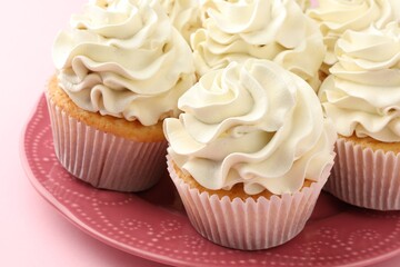 Tasty vanilla cupcakes with cream on pink table, closeup
