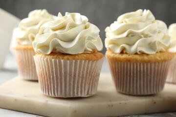 Tasty cupcakes with vanilla cream on table, closeup