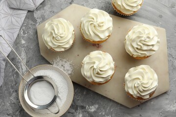 Tasty cupcakes with vanilla cream on grey table, top view
