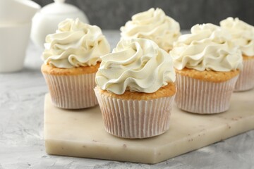Tasty cupcakes with vanilla cream on grey table, closeup