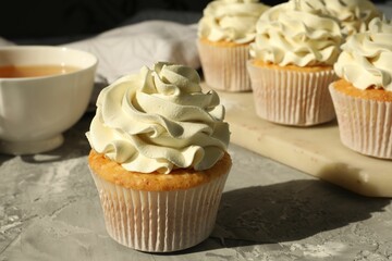 Tasty cupcakes with vanilla cream on grey table, closeup