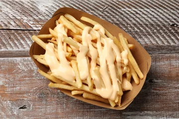 Tuinposter Delicious French fries with cheese sauce on wooden rustic table, top view © New Africa
