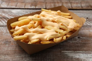Zelfklevend Fotobehang Delicious French fries with cheese sauce on wooden rustic table, closeup © New Africa