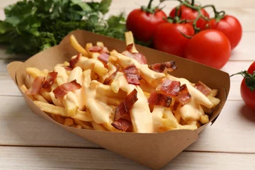 Foto op Canvas Tasty potato fries, cheese sauce, bacon and products in paper container on light wooden table, closeup © New Africa