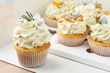 Tasty Easter cupcakes in box on wooden table, closeup