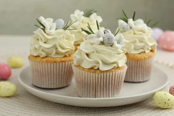 Poster Tasty Easter cupcakes with vanilla cream and candies on table, closeup © New Africa
