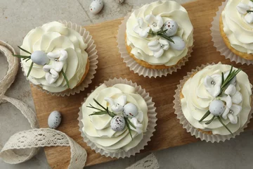 Gordijnen Tasty Easter cupcakes with vanilla cream and ribbon on gray table, flat lay © New Africa
