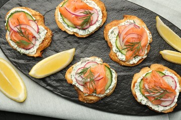 Tasty canapes with salmon, cucumber, radish and cream cheese on table, top view