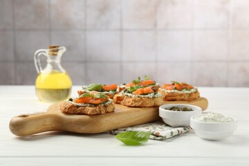 Tasty canapes with salmon, capers and sauce on white wooden table
