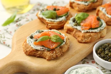 Gordijnen Tasty canapes with salmon, capers, cucumber and sauce on table, closeup © New Africa